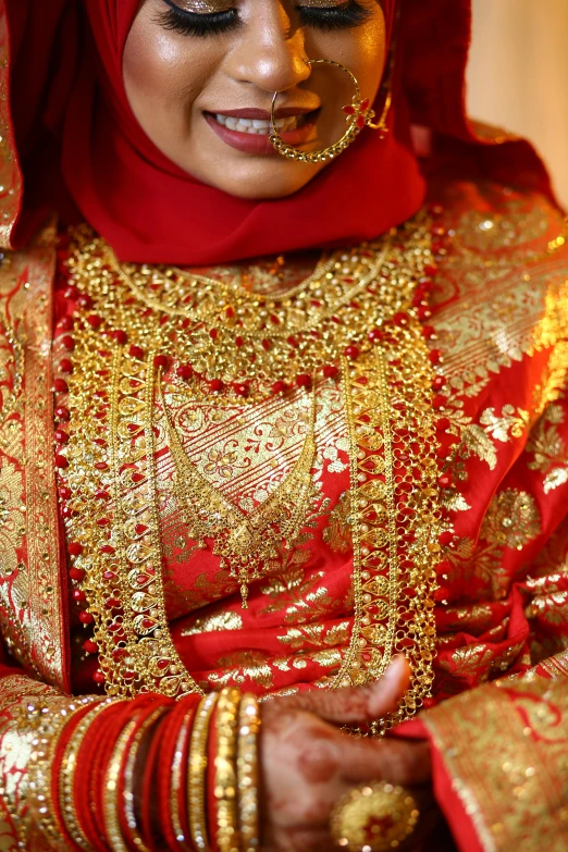 an indian woman in traditional red and gold wedding attire wearing jewellery