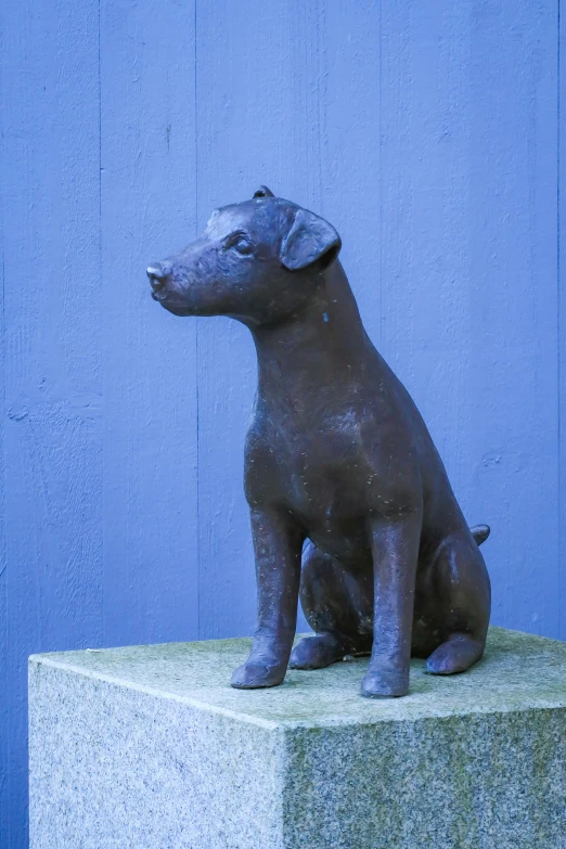 there is a statue of a dog sitting on a stone pedestal