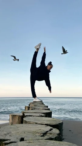 a man is doing a hand stand on a wooden pier