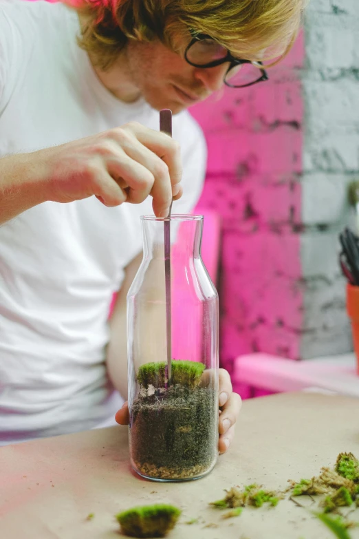 a young person making some type of substance in a glass bottle