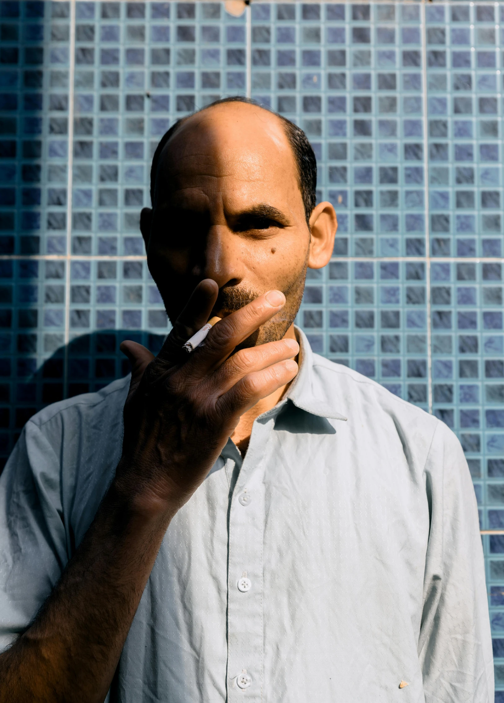 man holding cigarette in mouth next to wall