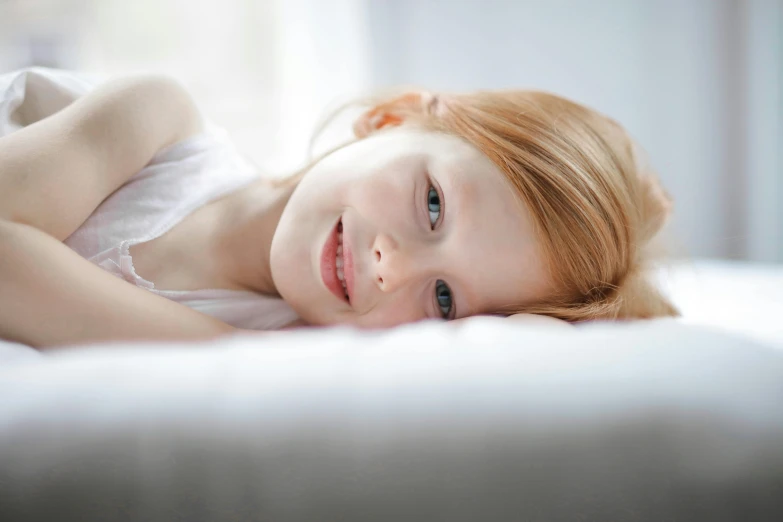 a little girl laying down on a bed