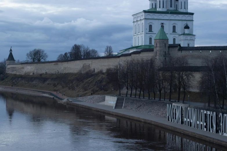 a white and green church sitting near a river