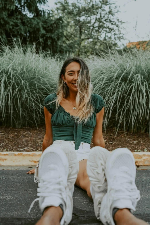 a young woman smiles for the camera as she sits outside