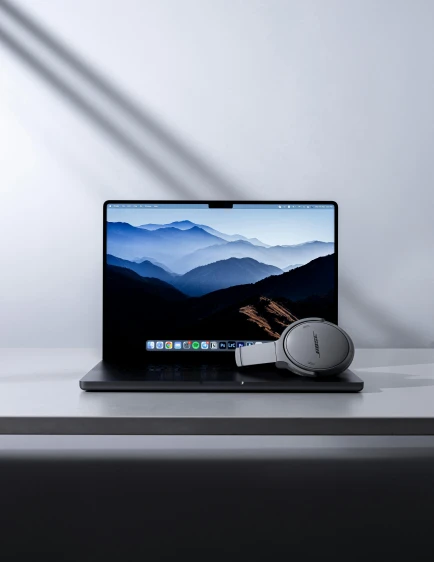 an apple laptop computer on a desk with headphones