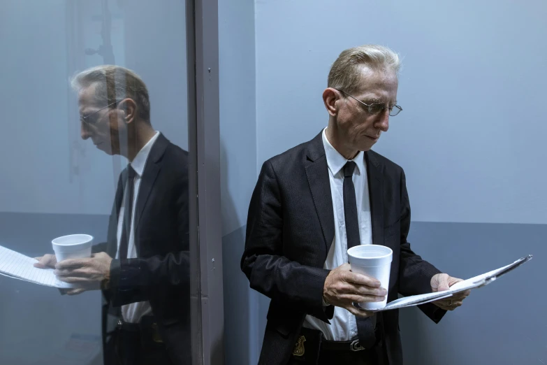 a man holding a cup and a newspaper