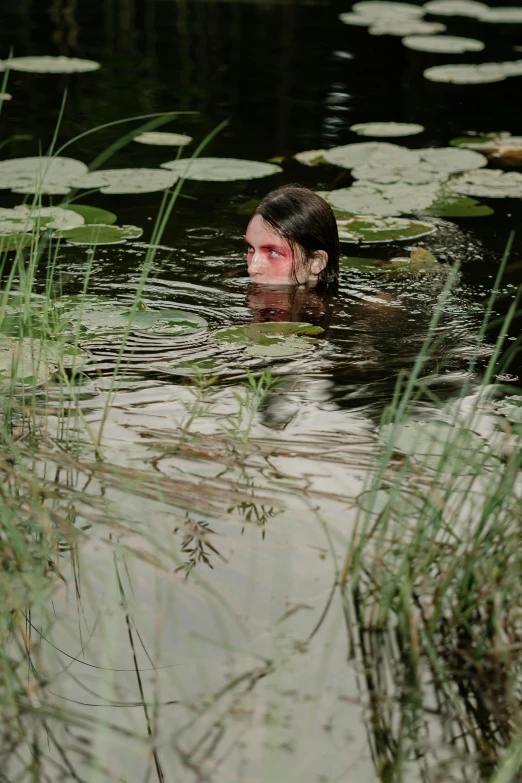 a man is swimming in a pond surrounded by water lilies