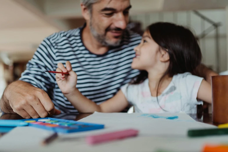 man and  drawing on table with crayons