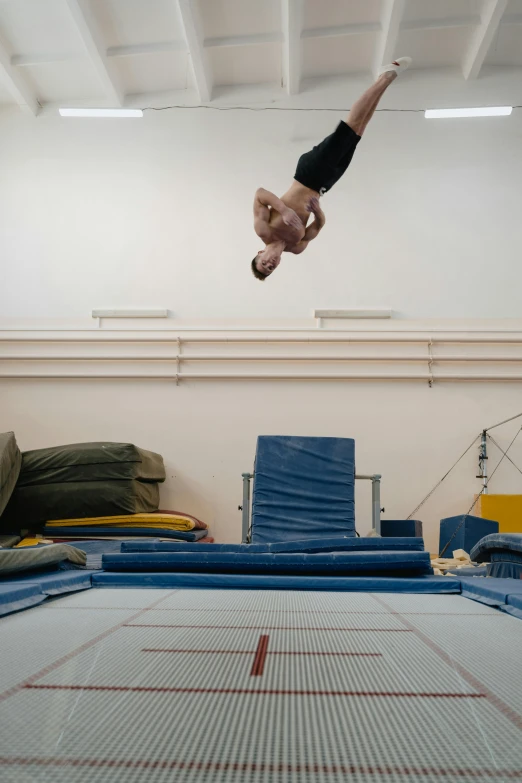 an upside down man in an indoor gymnastics gym