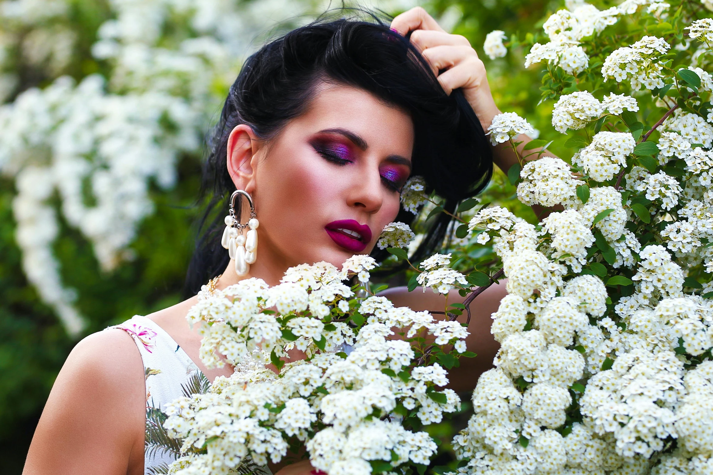 a woman is posing in front of a bush of flowers