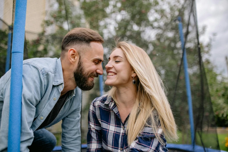 a smiling young couple sitting on the ground in a small trampoline