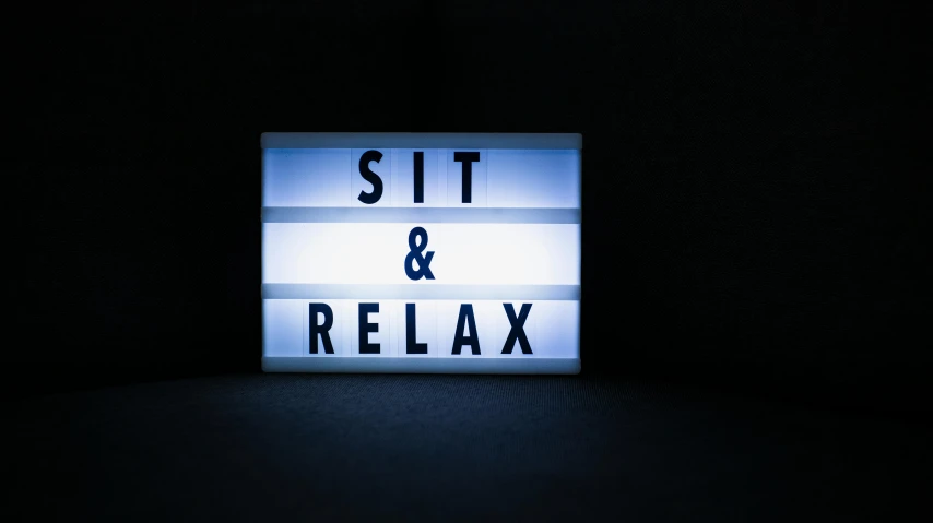 a lit sign that says sit and relax