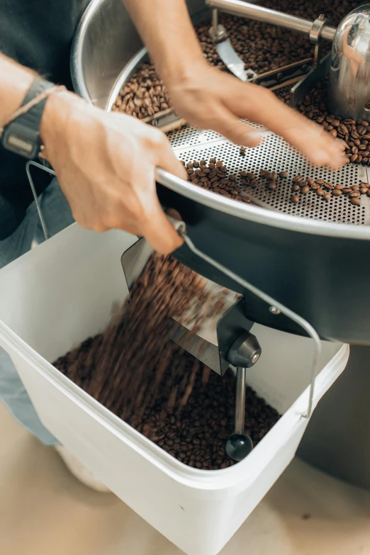 a person grating coffee beans in a metal strainer