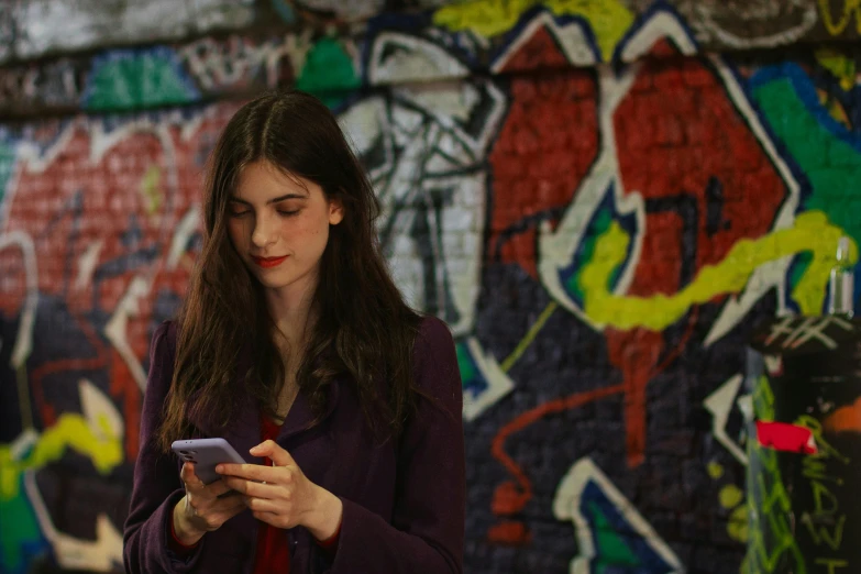 a woman standing in front of a colorful wall with graffiti