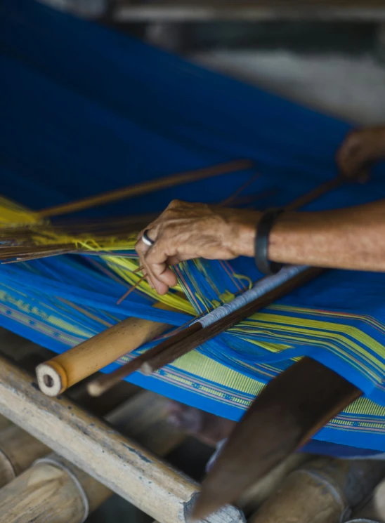 a person weaving fabric with wooden handles