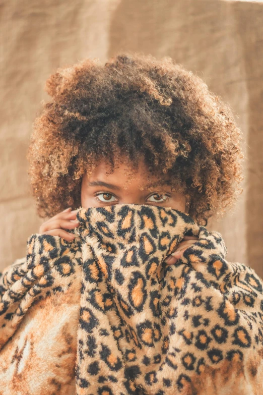 an african american woman covers her face with leopard fur