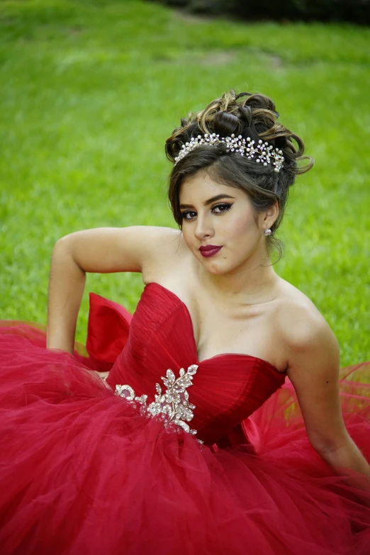 a girl wearing a dress with jewels sitting on the grass