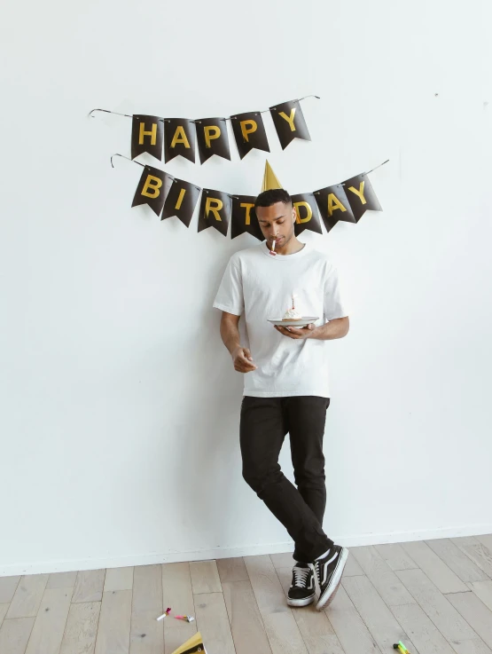 a man is holding a cake while standing in front of a birthday sign