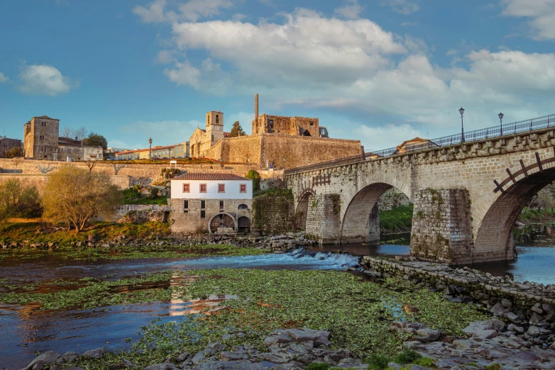 a stone bridge over a body of water in front of a city