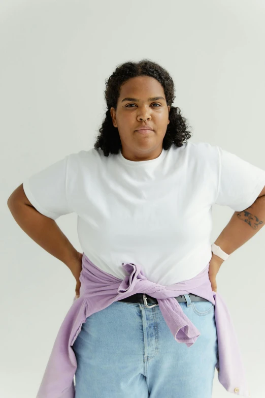 a woman wearing blue shorts and a white t - shirt with a purple bow