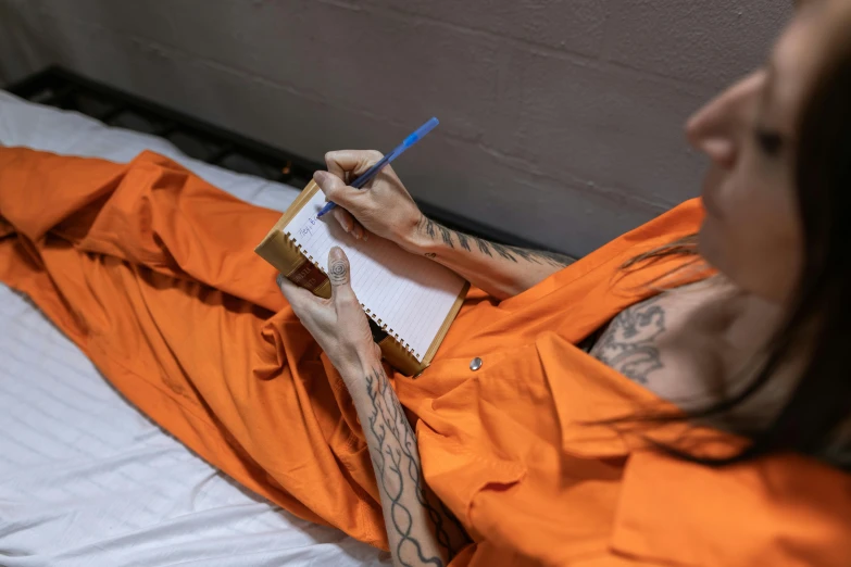 a person with tattoos writing on a notepad