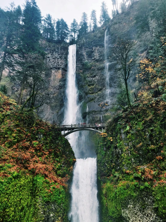 a tall waterfall with a bridge that goes over it