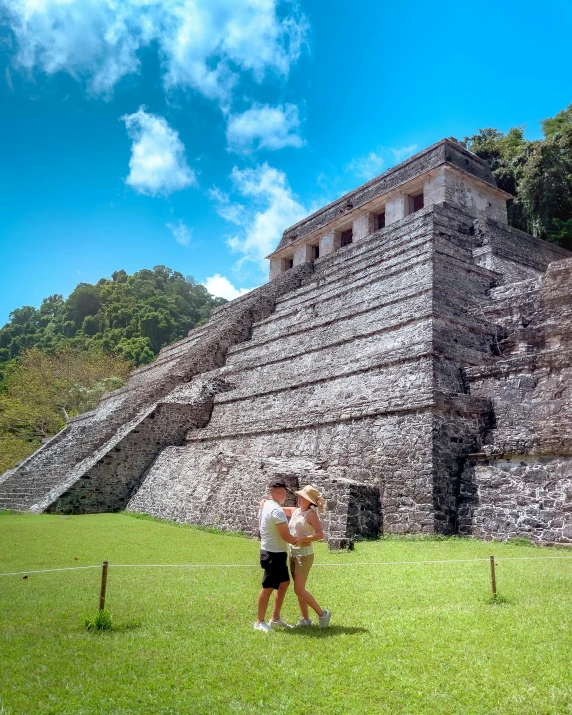 two people standing in front of a tall pyramid