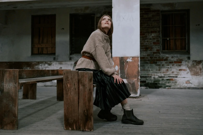 a woman leaning against a wooden fence with her feet on a table