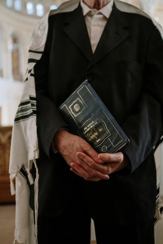 a priest is holding a book that reads, jesus