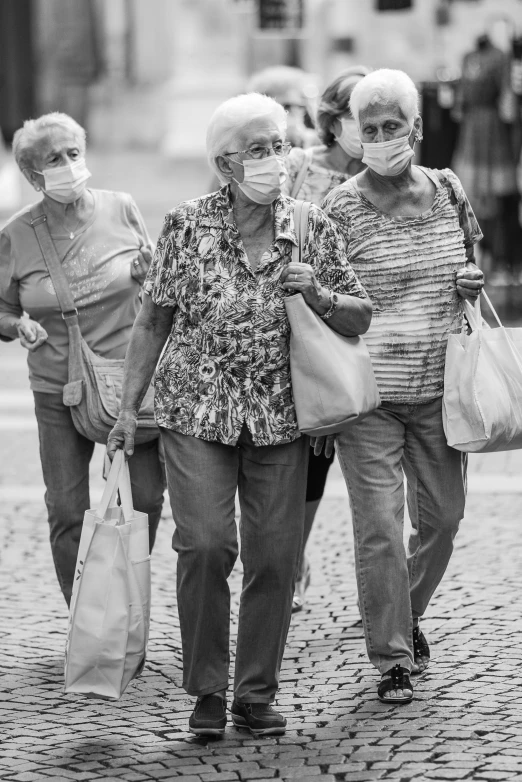 three older women in masks walking down the street