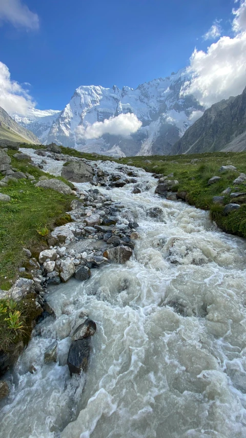 a beautiful river in the mountains with green grass