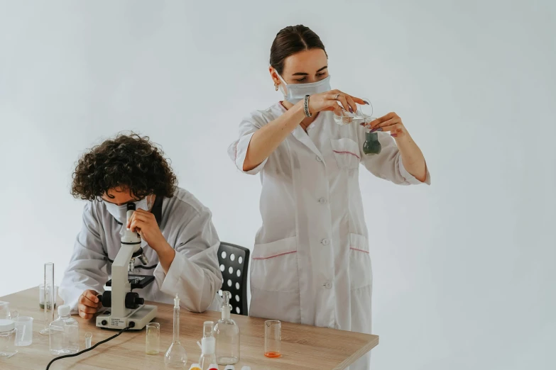 two people in lab coats work on various substances