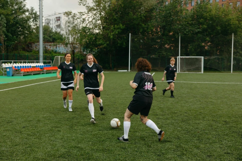 women playing soccer on a grassy field next to buildings