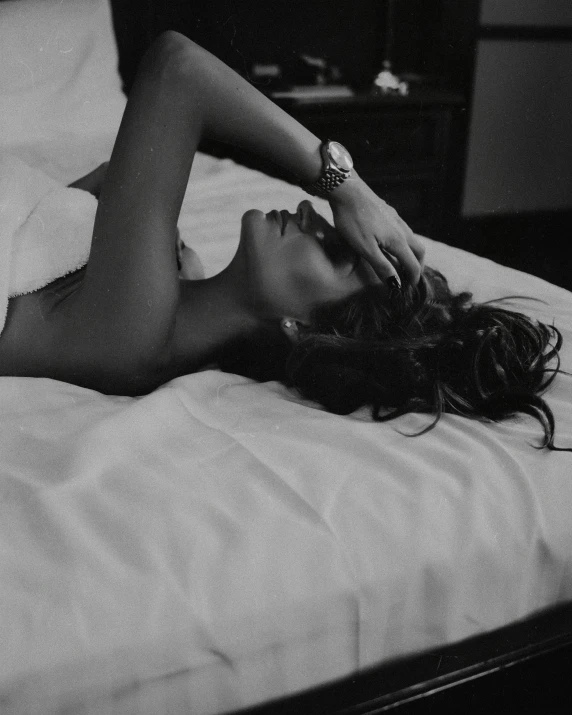 a woman laying on top of a bed in black and white