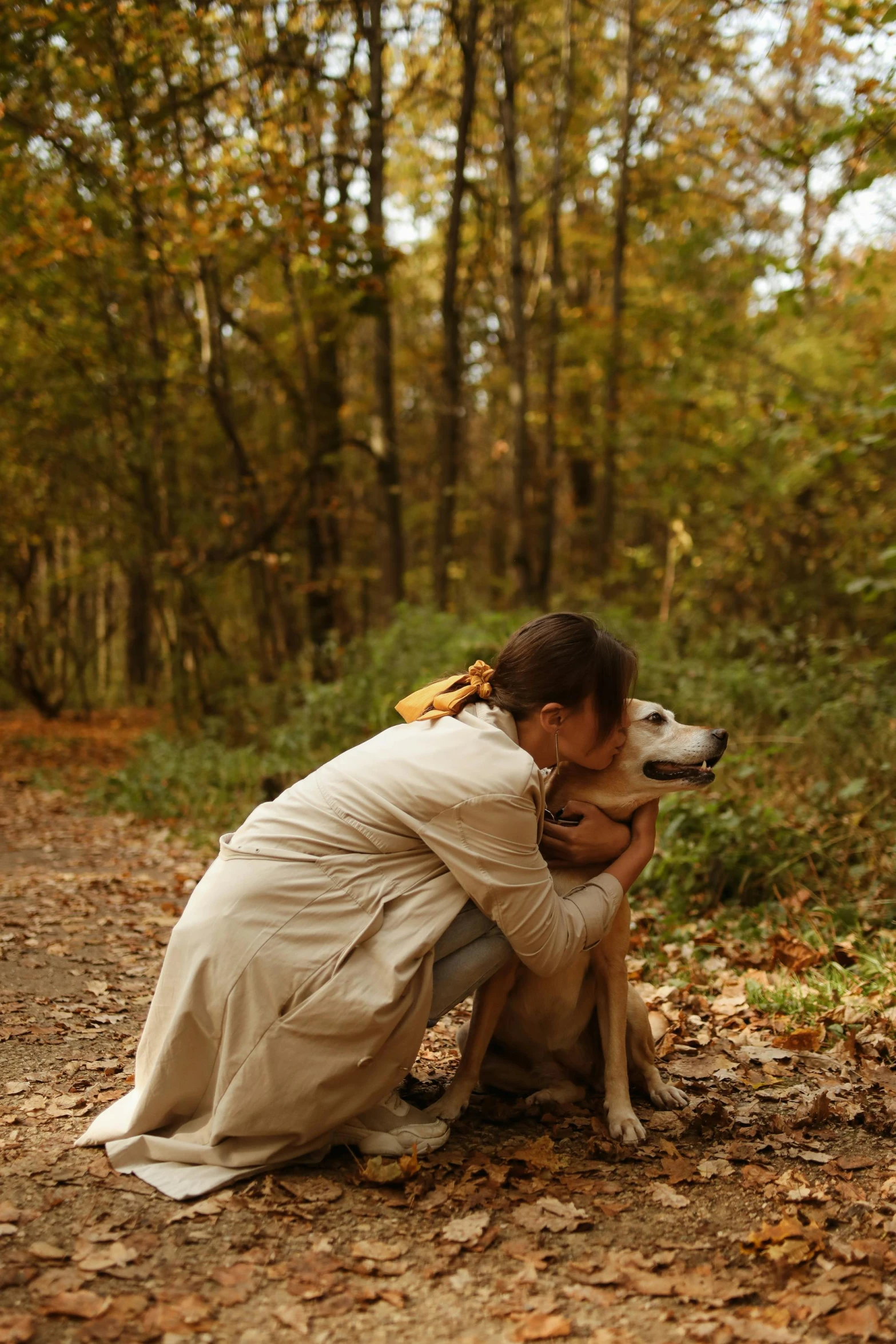woman and dog are sitting on leaves on the ground