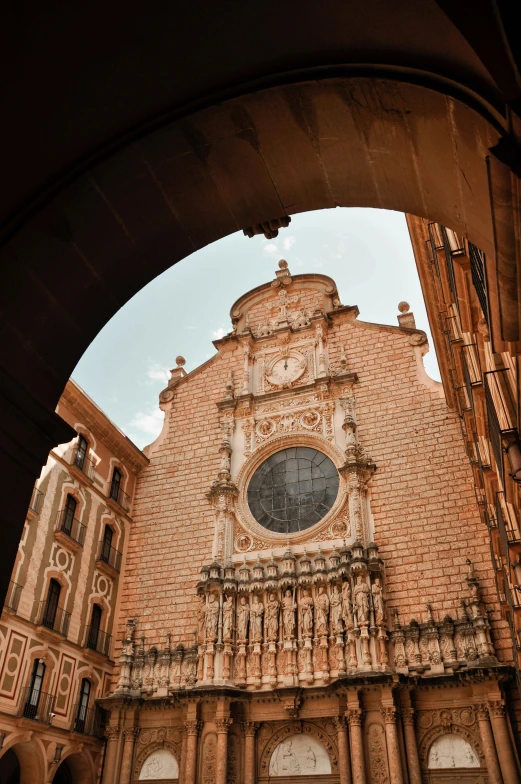 looking into an arched doorway at a brown building with a clock