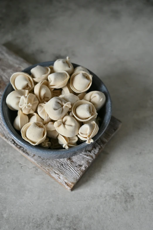 a bowl of garlic sits on a wooden board