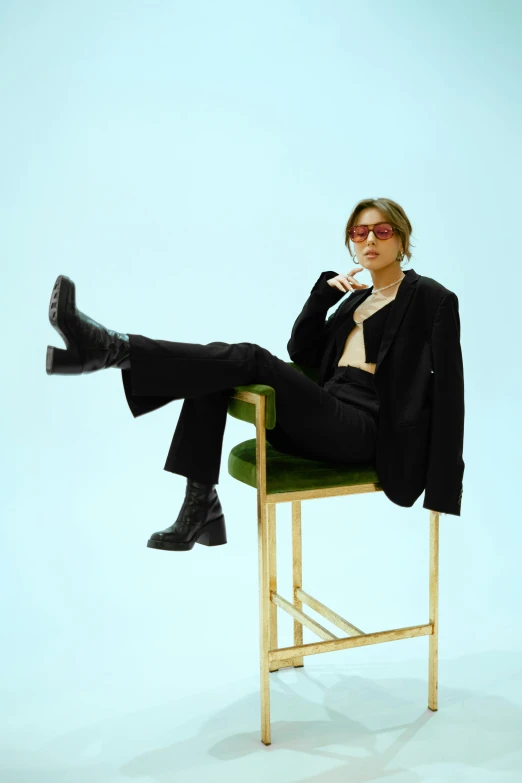 a woman in a black suit sitting on top of a wooden chair