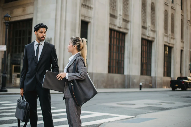 a man in business suit and a woman in grey checkered pants on the street talking