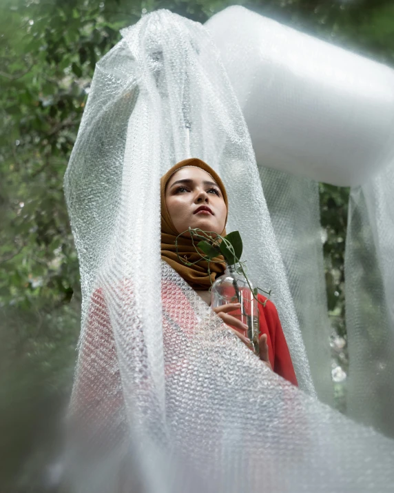 a beautiful woman standing in the woods holding a plant