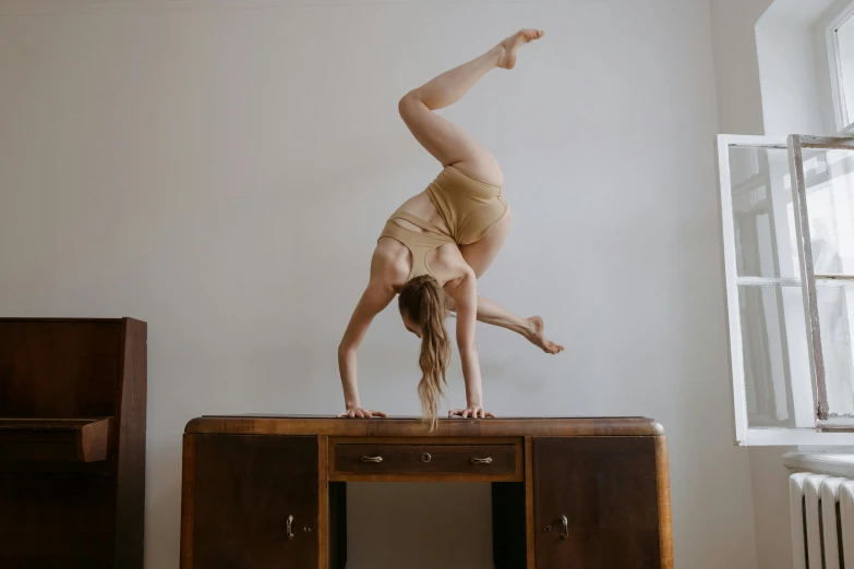 a little girl doing an acrobatic dance on a desk