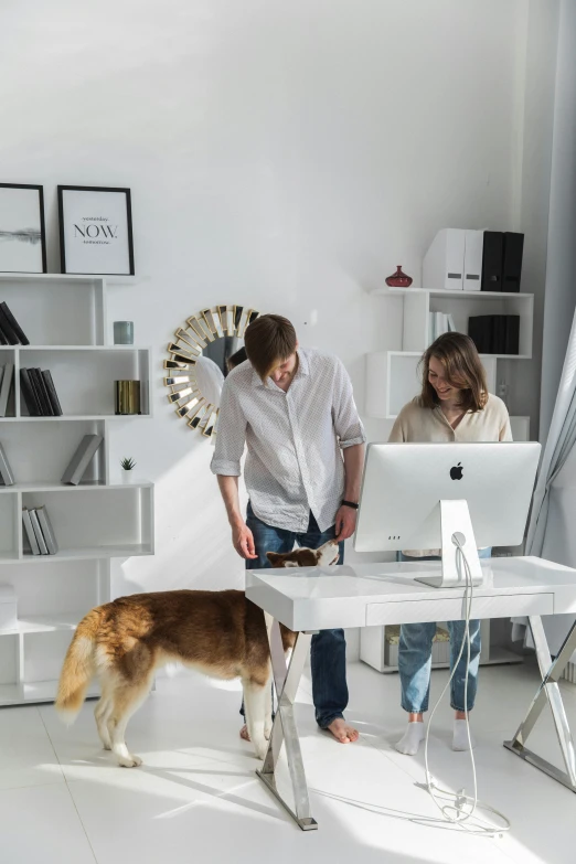 there are two people at a computer desk with a dog