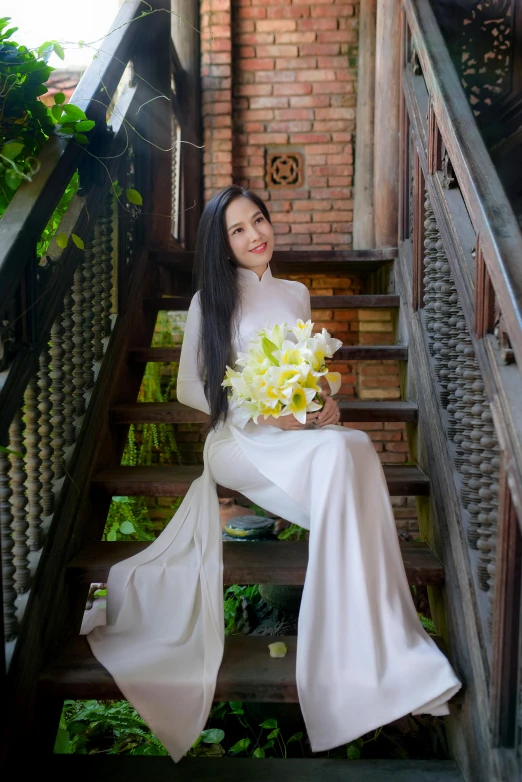 a woman holding a bouquet of flowers while sitting on stairs