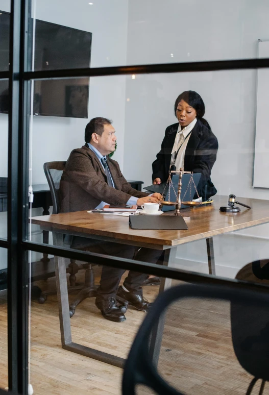 two people are sitting at a table in an office talking