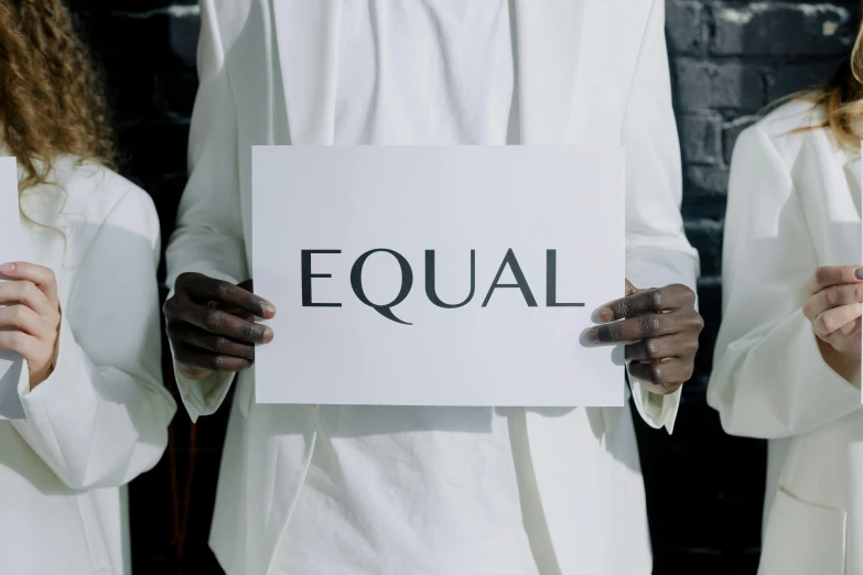 a man in white is holding a sign with equal written on it