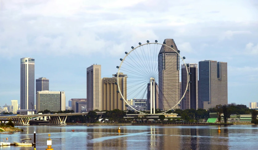 the ferris wheel is reflected in the water near the big city