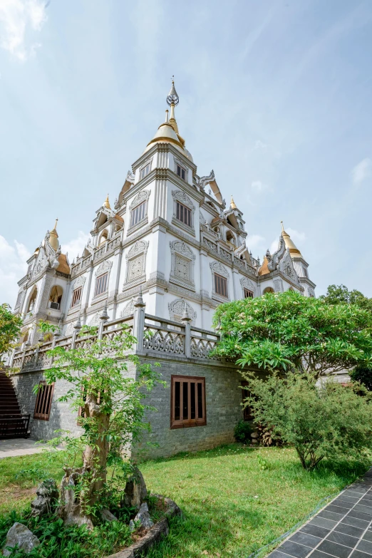 an ornate white building with gold trim sitting in the grass