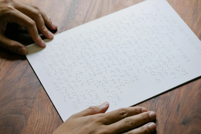 person touching a paper on a wood table