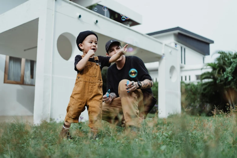 a father and son blowing bubbles outside their house