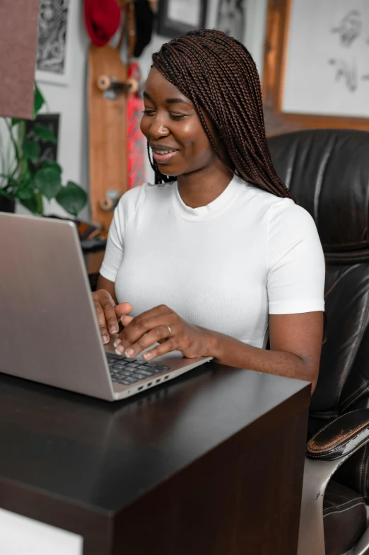 a woman smiles and uses her laptop at her desk